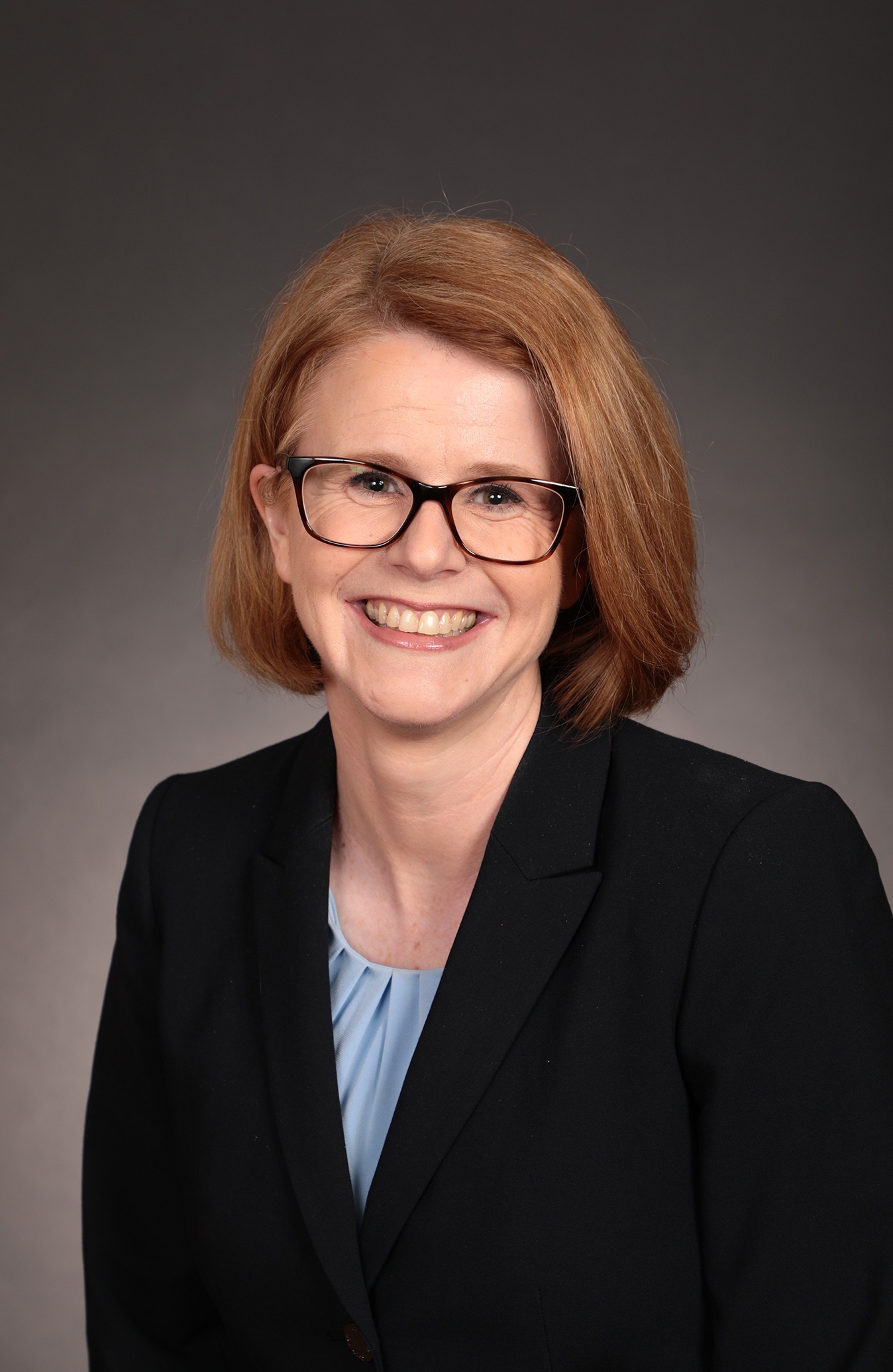 a woman wearing glasses and a black suit