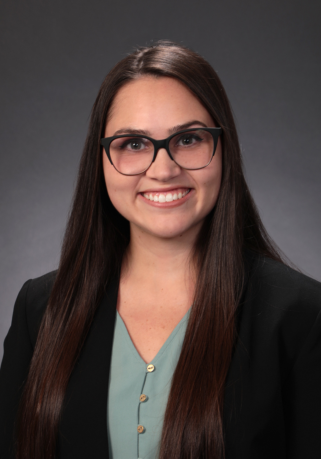 woman with dark hair in a suit and glasses